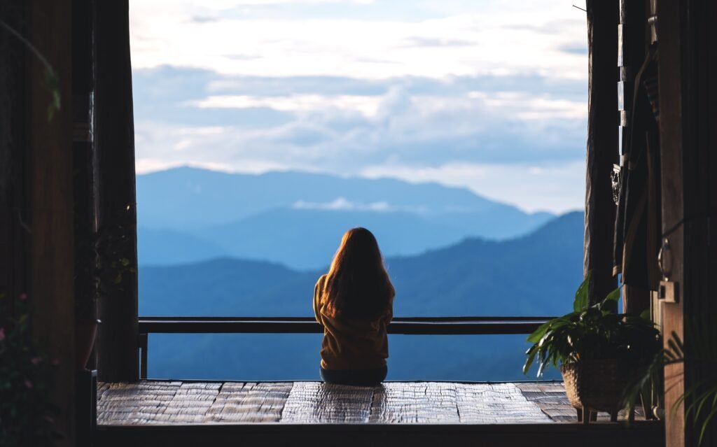 a female traveler sitting and looking at a beautiful mountain and nature view before sunset